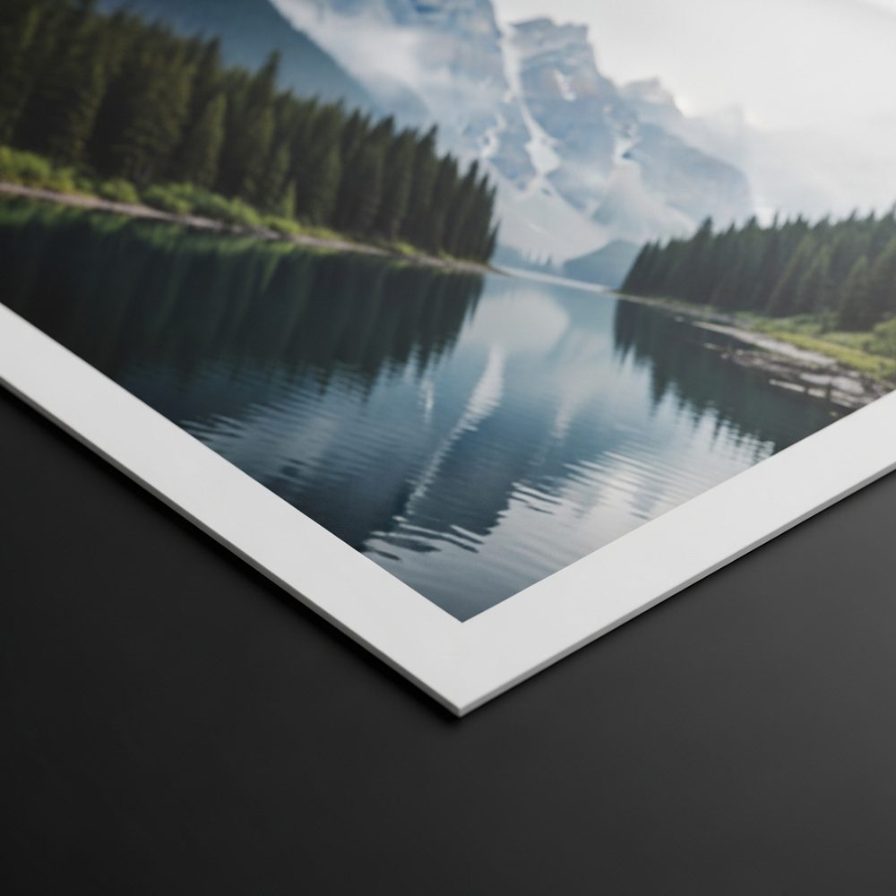 Corner of a matte fine-art print on a dark background, a mountain lake landscape on flat glare-free paper